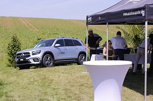 Ein silberner Mercedes-Benz SUV steht auf einer gr&uuml;nen Wiese neben einem schwarzen Pavillon des Autohauses Peter. Unter dem Zelt servieren Mitarbeiter Speisen an die Besucher des Reitturniers in Immenrode.