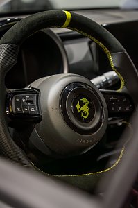 Detailaufnahme eines sportlichen Lenkrads mit gelbem Akzent.