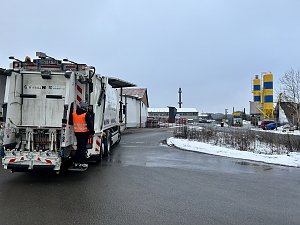 Verkaufsberater vom Autohaus Peter Andr&eacute; Schmidt steht auf der Trittstufe eines M&uuml;llfahrzeugs w&auml;hrend der Fahrt durch ein Industriegebiet.