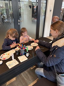 Kinder bemalen Ostereier. Ein Kind ist als Osterhase geschminkt.