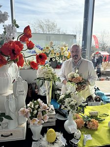 Dekorateur Frank L&uuml;dtke hinter seinem Stand aus Kunstblumengestecken.