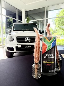 Tischdeko zum s&uuml;dafrikanischen Abend, im Hintergrund eine wei&szlig;e Mercedes G-Klasse.