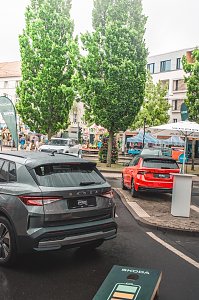 Graues und rotes Skoda Fahrzeug, B&auml;ume und St&auml;nde im Hintergrund.

